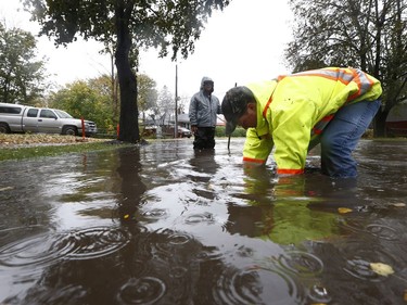 Adam Armstrong, Maintenance Coordinator for Ottawa City roads, lifts a sewer grate on Sanderson Drive during a rain storm in Ottawa Monday Oct. 30, 2017.