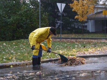 A man tries to clear the leaves off the sewer grate on Featherstone Drive during a rain storm in Ottawa Monday Oct. 30, 2017.