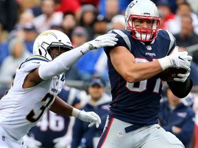 Rob Gronkowski of the New England Patriots evades a tackle from Adrian Phillips of the Los Angeles Chargers at Gillette Stadium on October 29, 2017 in Foxboro, Massachusetts.