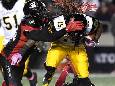 Hamilton Tiger-Cats running back Alex Green gets tackled by Ottawa Redblacks defensive lineman Jonathan Newsome. (THE CANADIAN PRESS/Justin Tang)