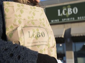 A woman carries a bag of purchased alcohol at province-owned LCBO store in Toronto, Ont. on April 1, 2014.