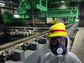 JAPAN-NUCLEAR-DISASTER-FUKUSHIMA

A member of the media wearing a protective suit and a mask walks in front of a fuel handling machine on the spent fuel pool inside the building housing the No. 4 reactor at Tokyo Electric Power Co.'s (Tepco) Fukushima Dai-ichi nuclear power plant in Okuma, Fukushima Prefecture, Japan on November 7, 2013.  Nuclear engineers in Japan are preparing to move uranium and plutonium fuel rods at Fukushima, their most difficult and dangerous task since the plant's runaway reactors were brought under control two years ago.  AFP PHOTO / Tomohiro Ohsumi/ POOLTOMOHIRO OHSUMI/AFP/Getty Images
TOMOHIRO OHSUMI, AFP/Getty Images