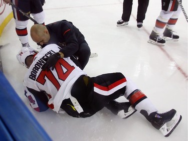 Defenceman Mark Borowiecki receives attention from a Senators training staff member after being checked into the boards by the Rangers' Brendan Smith in the third period. Borowiecki was taken to the dressing room and did not return to the game. Bruce Bennett/Getty Images