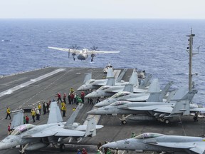 This handout picture taken on Nov. 17, 2017 shows a C-2A Greyhound (top left) assigned to Fleet Logistics Support Squadron (VRC) 30 launching from the flight deck of the Navy's forward-deployed aircraft carrier and flagship of Carrier Strike Group five, the aircraft carrier USS Ronald Reagan (CVN 76) in the Philippine Sea.