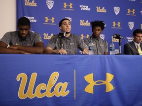 Flanked by Cody Riley, left, and Jalen Hill, third from left, UCLA basketball player LiAngelo Ball reads his statement as head coach Steve Alford listens during a news conference at UCLA Wednesday, Nov. 15, 2017, in Los Angeles. The three players were detained in Hangzhou following allegations of shoplifting last week before an NCAA college basketball game against Georgia Tech in Shanghai. (AP Photo/Jae C. Hong)