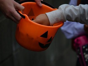 Cropped Image Of Hands Picking Candy From Halloween Basket