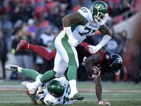 Saskatchewan Roughriders' Rakim Cox (77) and Derrick Moncrief (42) tackle Ottawa Redblacks' William Powell (29) during second half Eastern semifinal CFL action in Ottawa on Sunday, Nov. 12, 2017.