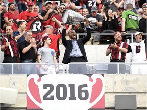 Former quarterback Henry Burris raises the Grey Cup after a banner was unveiled to mark the team's victory, before the Redblacks' season opener again the Calgary Stampeders in Ottawa on Friday, June 23, 2017.