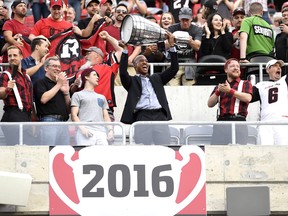 2016 Ottawa Redblacks quarterback Henry Burris raises the Grey Cup after a banner was unveiled to mark the team's victory, before the Redblacks' season opener again the Calgary Stampeders in Ottawa on Friday, June 23, 2017. THE CANADIAN PRESS/Justin Tang
