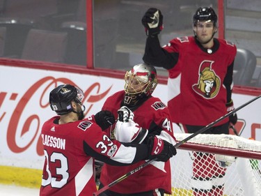 Ottawa Senators goalie Craig Anderson is congratulated by defenceman Fredrik Claesson as defenceman Chris Wideman skates past the net at the end of the game.