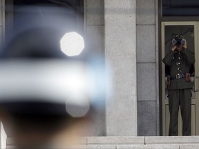 In this Sept. 25, 2013, file photo, a North Korean soldier, right, looks at the south side through a pair of binoculars as a South Korean soldier, left, stands guard at the truce village of Panmunjom in the Demilitarized Zone which has separated the two Koreas since the Korean War, in Paju, north of Seoul, South Korea. North Korean soldiers shot at and wounded a fellow soldier who was crossing a border village in an attempt to defect to South Korea on Monday, Nov. 13, 2017, the South's military said. (AP Photo/Lee Jin-man, File)