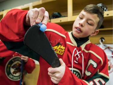 Eastern Ontario's Carey Terrance prepares his stick in the dressing room before Sunday's major peewee AAA championship game.