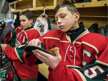 The Eastern Ontario Wild's Ethan Montroy, left, and Carey Terrance wax their sticks before their major peewee AAA final against the Providence Capitals on Sunday.