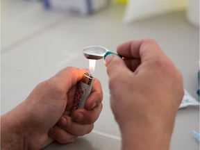 A drug user prepares heroin for injection at a pop up safe injection site.