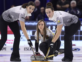 Skip Rachel Homan looks down the sheet as Lisa Weagle (left) and Joanne Courtney sweep during Saturday's semifinal. (THE CANADIAN PRESS)