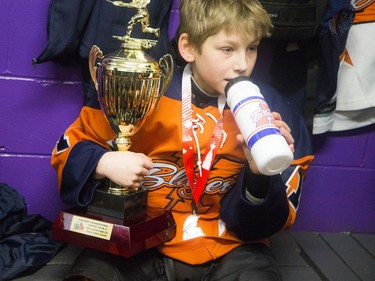 Kanata's Kian Gauthier keeps a tight grip on the championship trophy as he sits in the dressing room after the game.   Ashley Fraser/Postmedia