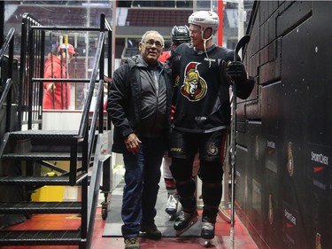 Newly retired Chris Neil, coming off the ice, catches up with Wade Redden's dad, Gord.