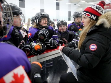 Yukon peewee girls team assistant coach Candice MacEachen goes over strategy with her players between periods of Friday's game.  Julie Oliver/Postmedia