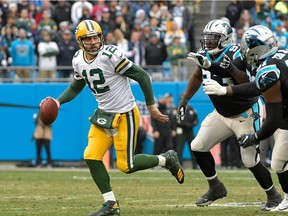 Aaron Rodgers #12 of the Green Bay Packers rolls out under pressure from the Carolina Panthers defense during their game at Bank of America Stadium on December 17, 2017 in Charlotte, North Carolina. The Panthers won 31-24.