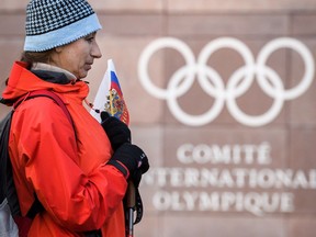 A supporter stands with a Russian flag in front of the logo of the International Olympic Committee (IOC) at the headquarters on December 5, 2017 in Pully near Lausanne. The International Olympic Committee meets to decide whether to bar Russia from the 2018 Winter Olympics for doping violations, in one of the weightiest decisions ever faced by the Olympic movement.