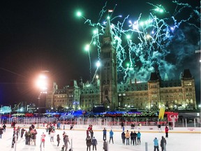 Skaters on the Canada 150 ice rink look on as fireworks explode above Centre Block's Peace Tower during the illumination launch ceremony of Christmas Lights Across Canada on Parliament Hill in Ottawa on Thursday, Dec. 7, 2017.