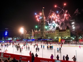 Fireworks explode above Centre Block's Peace Tower as skaters look on from the Canada 150 ice rink during the illumination launch ceremony of Christmas Lights Across Canada on Parliament Hill Dec.