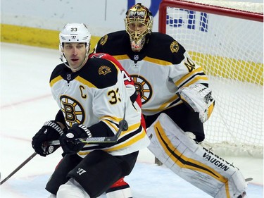 Bruins captain Zdeno Chara knocks down the puck as goalie Tuukka Rusk looks on during second-period play at Canadian Tire Centre on Saturday.