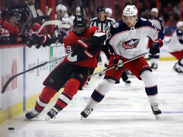 The Senators' Johnny Oduya, left, and the Blue Jackets' Josh Anderson race for the puck along the boards during the first period of Friday's game.