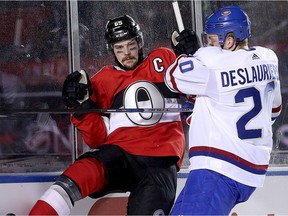 Erik Karlsson is checked into the boards by Nicolas Deslauriers in the second period as the Ottawa Senators take on the Montreal Canadiens in the 2017 Scotiabank NHL 100 Classic outdoor hockey game at TD Place in Ottawa.  Photo by Wayne Cuddington/ Postmedia