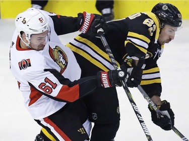 Senators right-winger Mark Stone (61) checks Bruins left-winger Brad Marchand (63) during the first period.