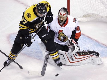 Senators goalie Craig Anderson, right, tries to poke the puck away from Bruins centre Patrice Bergeron during the third period.