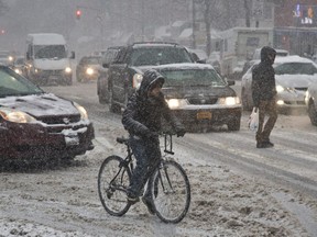 A bike rider attempts to get around in a snowstorm in Brooklyn. Why, wonders a letter writer, is the same done in Ottawa?