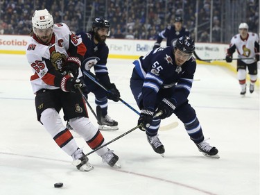 Ottawa Senators defenceman Erik Karlsson (left) takes the puck from Winnipeg Jets centre Mark Scheifele in Winnipeg on Sun., Dec. 3, 2017.