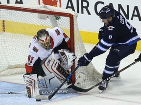 Winnipeg Jets forward Andrew Copp (centre) jams the puck at Ottawa Senators goaltender Craig Anderson after leaving Thomas Chabot (right) behind in Winnipeg on Sun., Dec. 3, 2017.