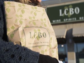 In this April 1, 2014 file photo, a woman carries an LCBO shopping bag filled with alcohol in Toronto, Ont.