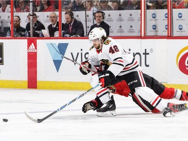 OTTAWA, ON - JANUARY 9: Vinnie Hinostroza #48 of the Chicago Blackhawks uses his body to keep the puck from a falling Colin White #36 of the Ottawa Senators in the first period at Canadian Tire Centre on January 9, 2018 in Ottawa, Ontario, Canada.