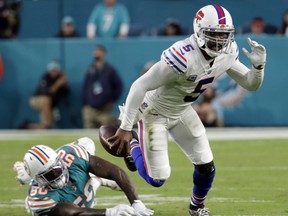 FILE - In this Sunday, Dec. 31, 2017, file photo, Buffalo Bills quarterback Tyrod Taylor (5) escapes a tackle by Miami Dolphins defensive end Andre Branch (50).