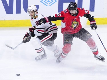 Chicago Blackhawks' Ryan Hartman, left, and Ottawa Senators' Erik Karlsson battle for the puck during the first period of NHL hockey action in Ottawa on Tuesday, Jan. 9, 2018.