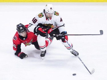 Chicago Blackhawks' Vinnie Hinostroza battles for the puck against Ottawa Senators' Colin White during the first period of NHL hockey action in Ottawa on Tuesday, Jan. 9, 2018.