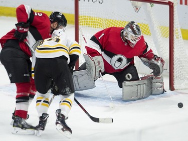 Ottawa Senators defenceman Dion Phaneuf ties up the Boston Bruins' Danton Heinen as Senators goaltender Mike Condon keeps an eye on the puck.