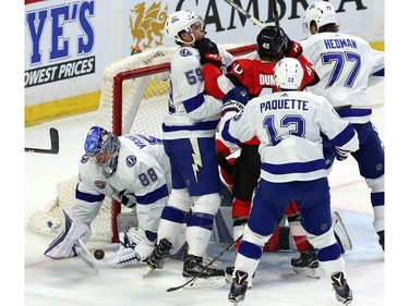 Tampa Bay Lightning goaltender Andrei Vasilevskiy (88) attempts to smother the puck as a crowd gathers around his goal crease.