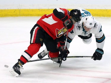 The Ottawa Senators' Johnny Oduya (29) and the San Jose Sharks' Joonas Donskoi (27) fight for the puck.