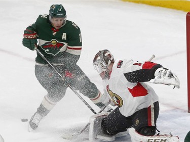 Ottawa Senators goaltender Mike Condon, right, stops a shot as the puck slides under Minnesota Wild's Zach Parise in the second period of an NHL hockey game Monday, Jan. 22, 2018, in St. Paul, Minn.