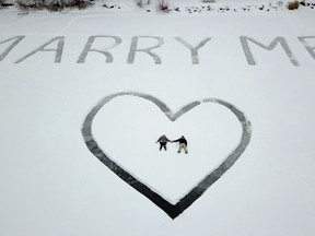 In this Jan. 7, 2018 photo provided by Ed Becker, Gavin Becker and his long-time girlfriend Olivia Toft lay in the snow after he proposed on Eight Crow Wing Lake near Nevis, Minn.