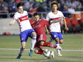 Ottawa Fury's Sito Seoane battles with Toronto FC's Mitchell Taintor, left, while Toronto FC's Tsubasa Endoh, right, looks on during the second half their Canadian championship semifinal soccer match at TD Place in Ottawa on Tuesday, May 23, 2017.