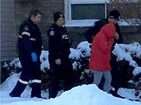 Police escort a woman outside 12 Redberry Pkwy. believed to be the mother of a baby who was allegedly abandoned at a nearby Keele St. and Lawrence Ave. plaza. (Joe Warmington/Toronto)