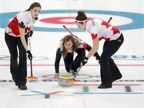 Rachel Homan, skip for Team Canada, throws the rock as teammates Lisa Weagle, left and Joanne Courtney sweep during their game against Japan on Monday. Leah Hennel/Postmedia
