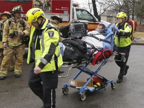 Paramedics evacuate a woman from a fire on Riverside Drive in Ottawa, on Wednesday, February 21, 2018.