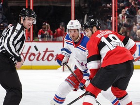 Linesman James Tobias, left, looks on as the Senators' Derick Brassard (19) and the Rangers' Peter Holland track the puck after a faceoff in the first period of Saturday's game.