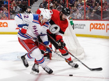 Ben Harpur of the Ottawa Senators battles for the loose puck against Peter Holland of the New York Rangers.